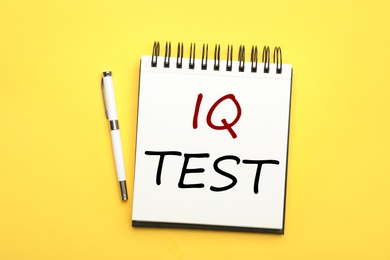 Image of Notebook with text IQ Test and pen on yellow background, flat lay