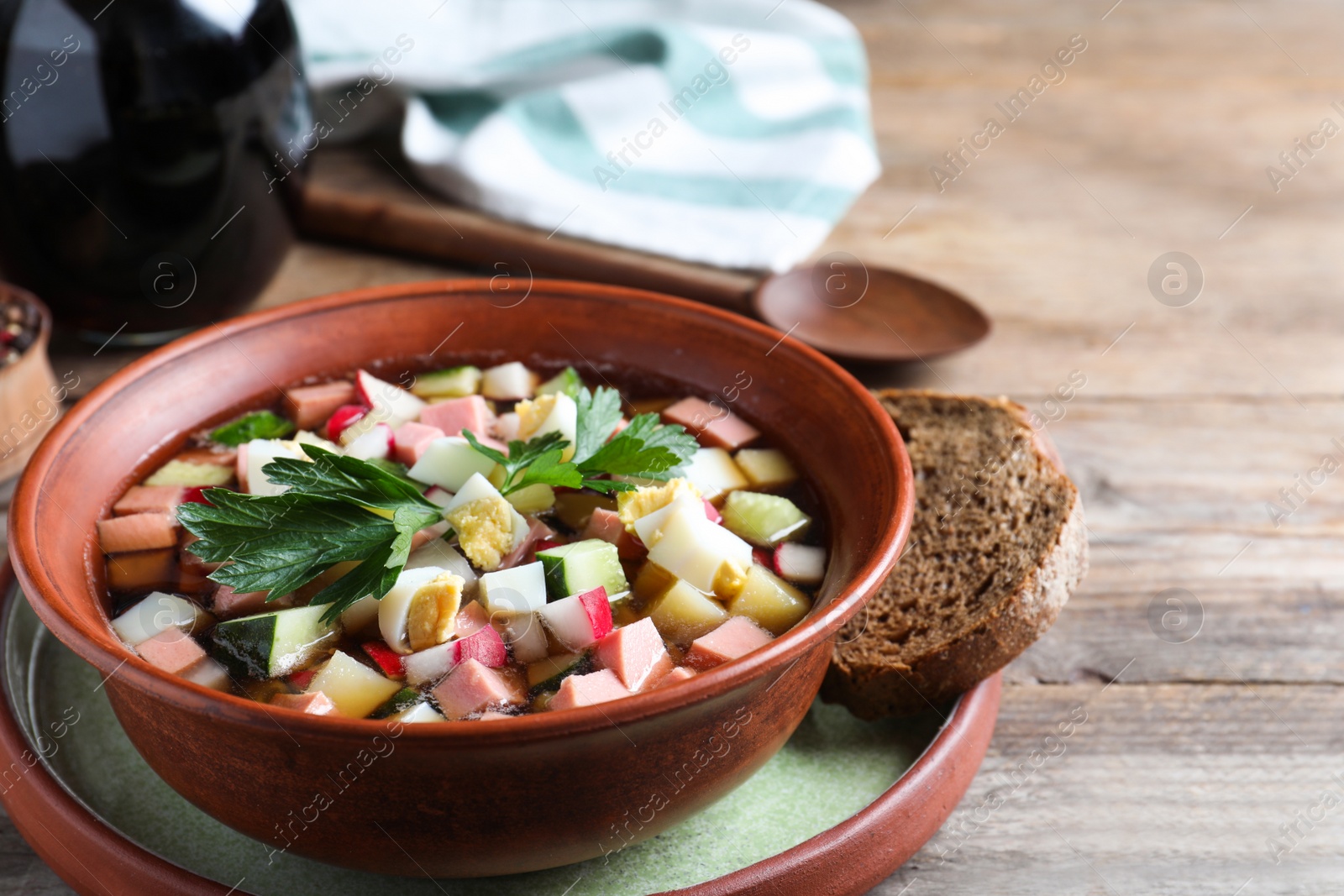 Photo of Delicious cold okroshka with kvass served on wooden table, closeup. Traditional Russian summer soup