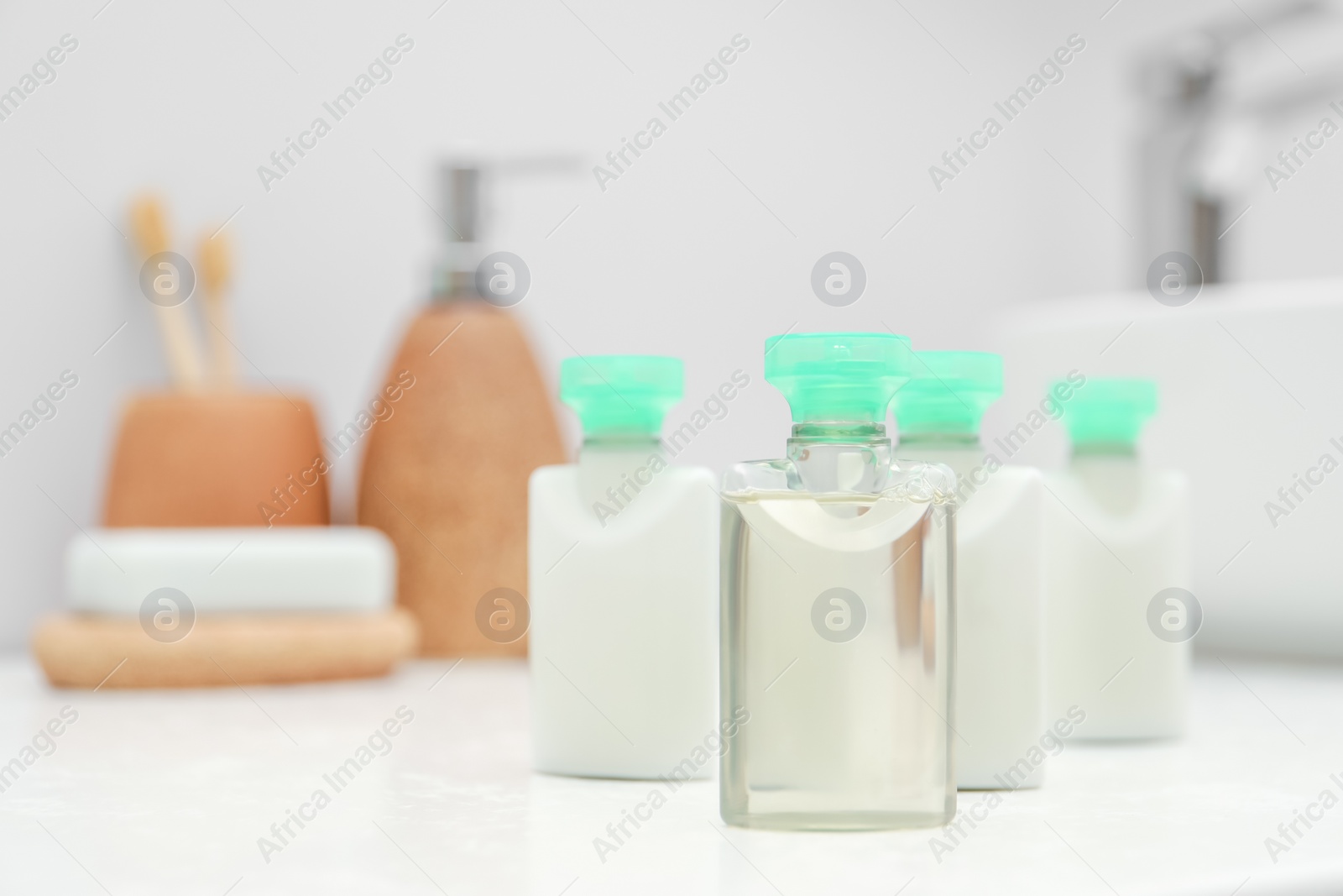 Photo of Mini bottles of cosmetic products on white countertop in bathroom. Space for text