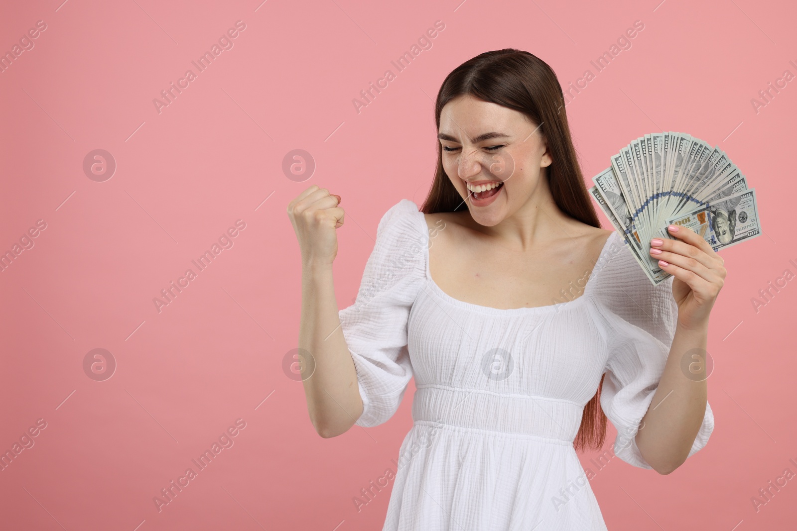 Photo of Excited woman with dollar banknotes on pink background, space for text