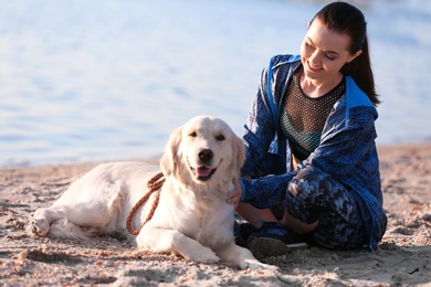 Photo of Young woman with her dog together on beach. Pet care