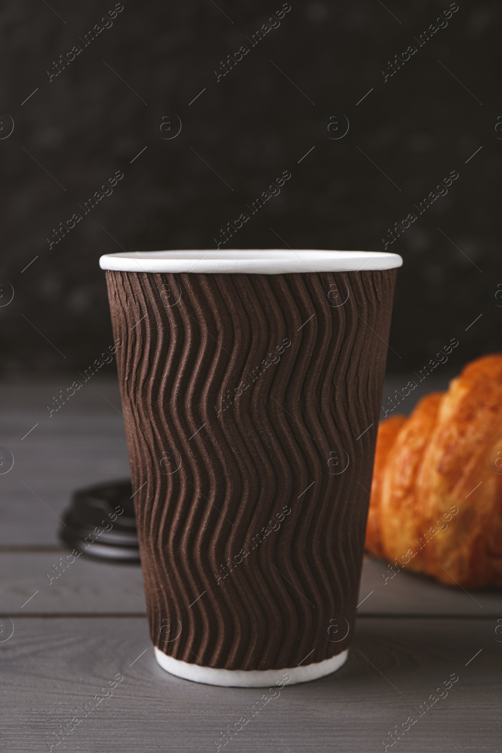 Photo of Coffee to go. Paper cup with tasty drink on grey wooden table