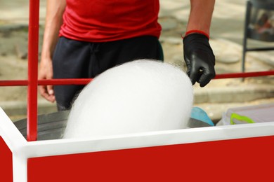 Photo of Man making cotton candy with machine outdoors, closeup