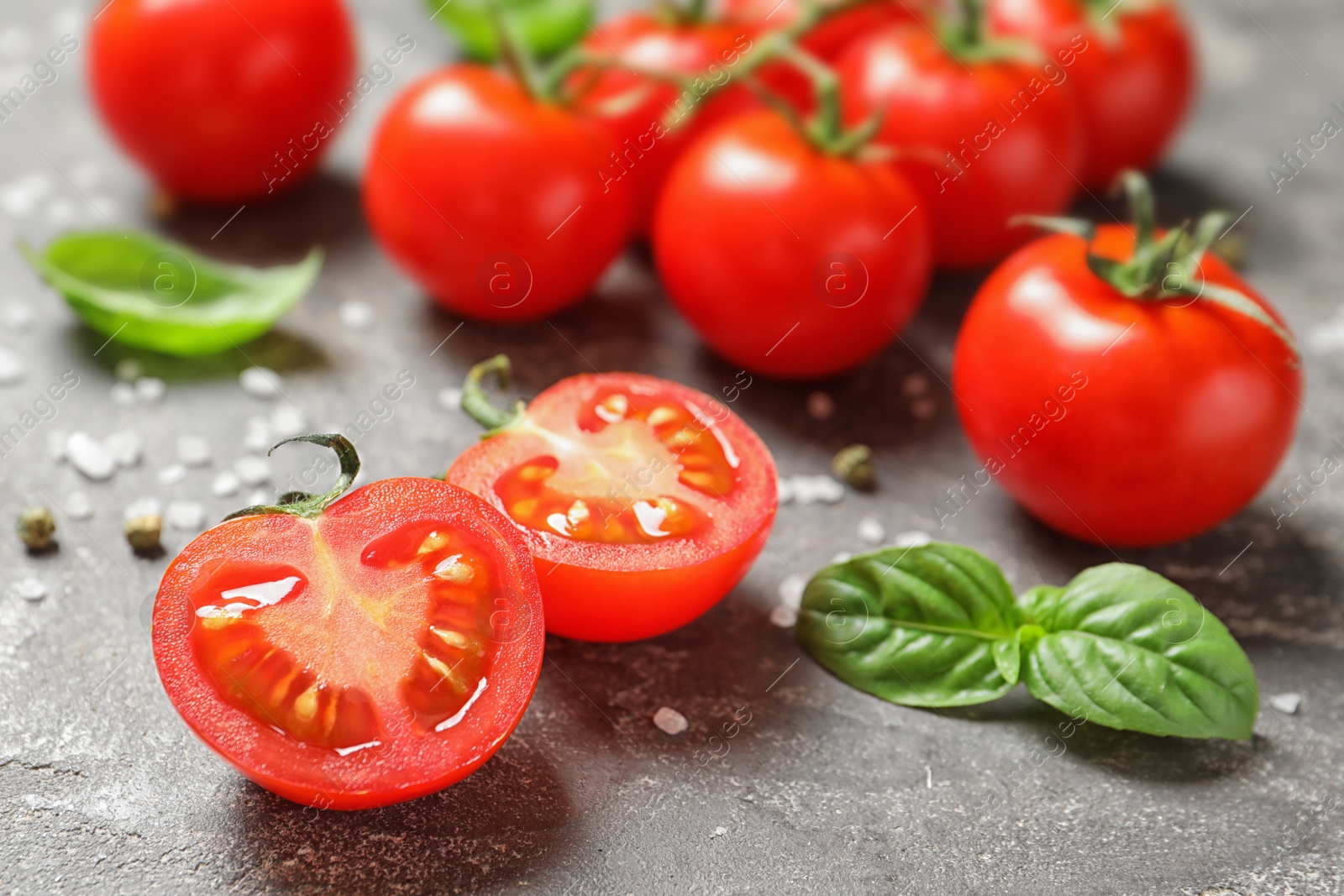 Photo of Cherry tomatoes with spice and basil on stone background