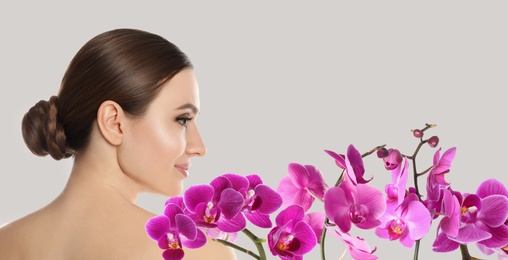 Image of Beautiful young woman and orchid flowers on light background, banner design. Spa portrait