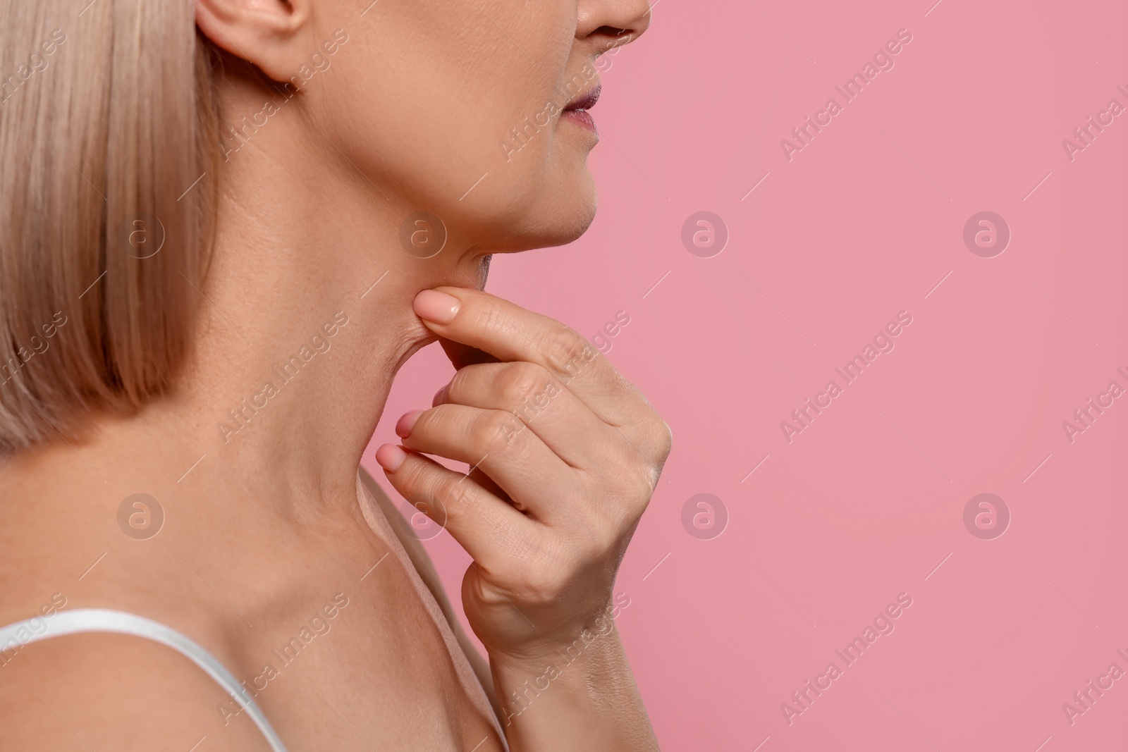 Photo of Woman touching her neck on pink background, closeup. Space for text