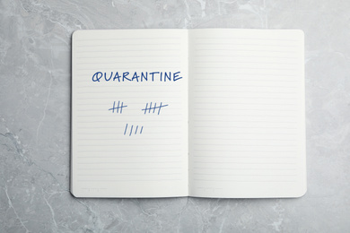 Image of Open notebook on marble table, top view. Counting days of quarantine during coronavirus outbreak 