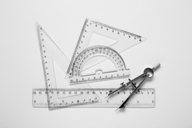 Photo of Different rulers and compass on white background, top view