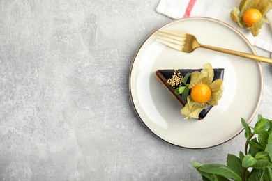 Photo of Piece of tasty cake decorated with physalis fruit on light grey table, flat lay. Space for text