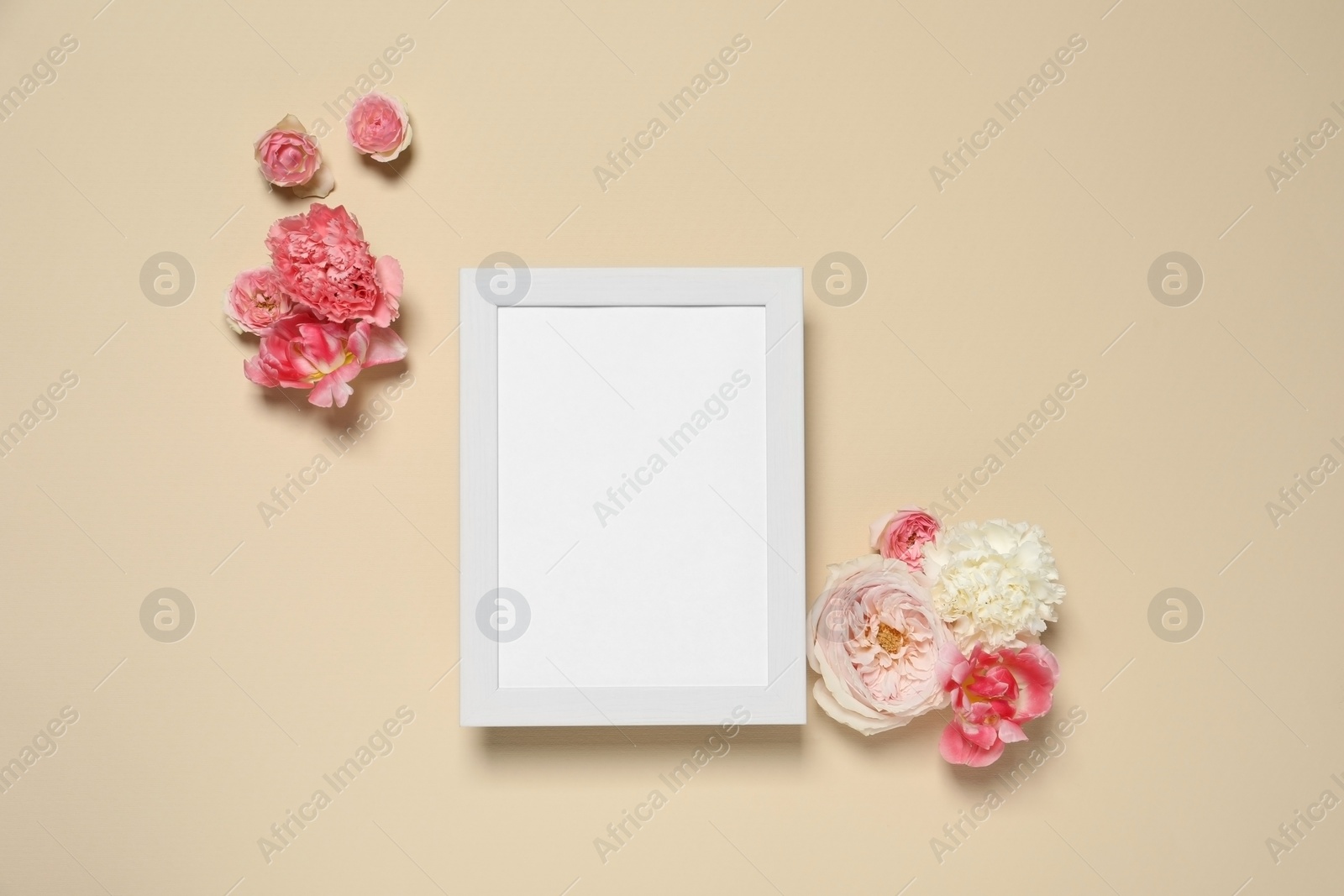 Photo of Empty photo frame and beautiful flowers on beige background, flat lay. Space for design