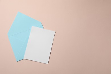 Letter envelope and card on beige background, top view. Space for text