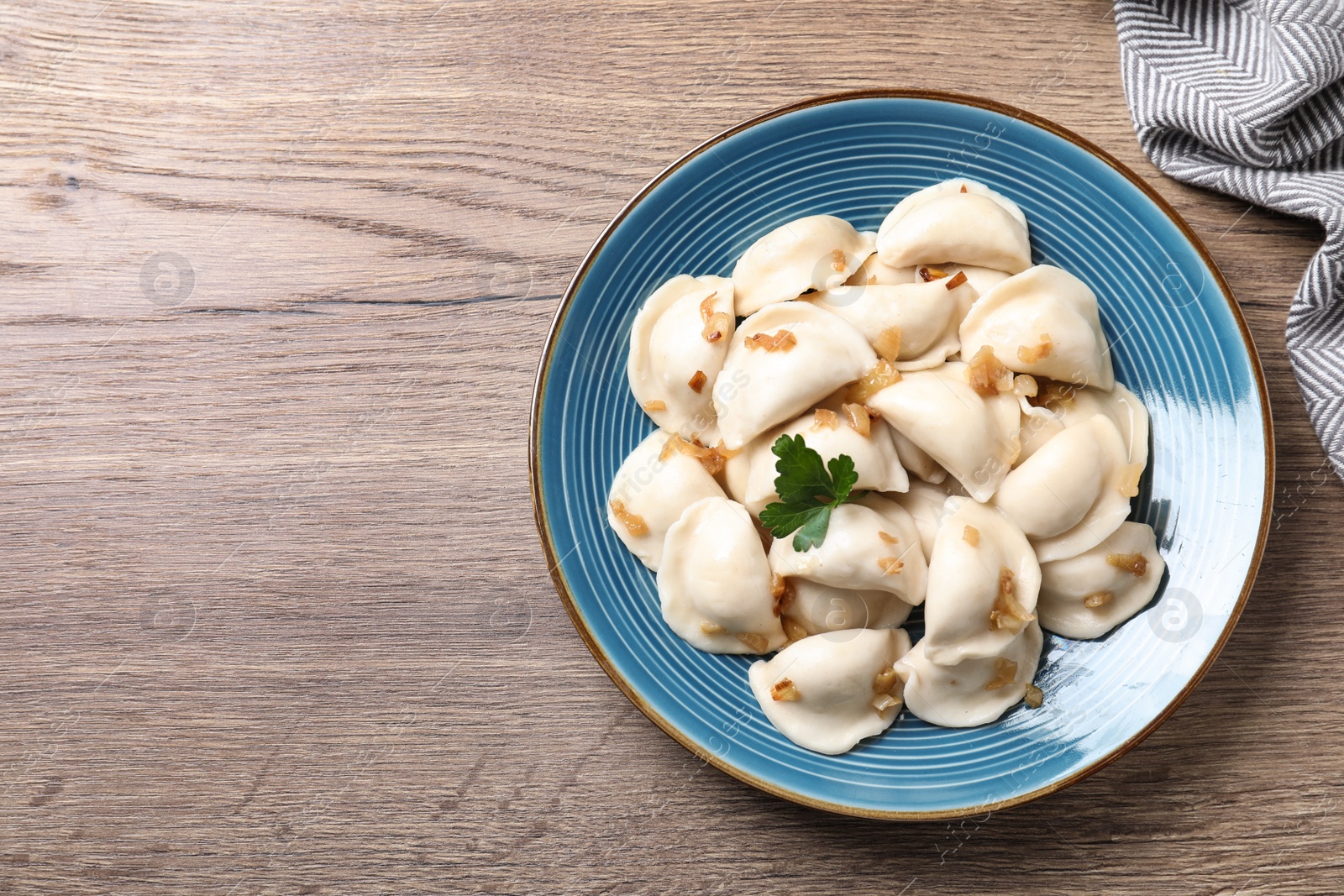 Photo of Plate of tasty cooked dumplings on wooden table, top view with space for text