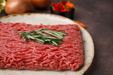 Photo of Fresh raw ground meat and rosemary on brown table, closeup