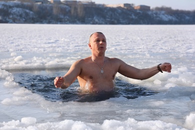 Photo of MYKOLAIV, UKRAINE - JANUARY 06, 2021: Man immersing in icy water on winter day