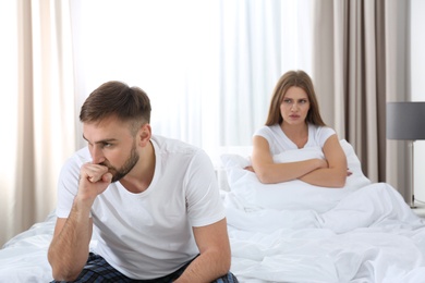 Photo of Young couple with relationship problems ignoring each other in bedroom