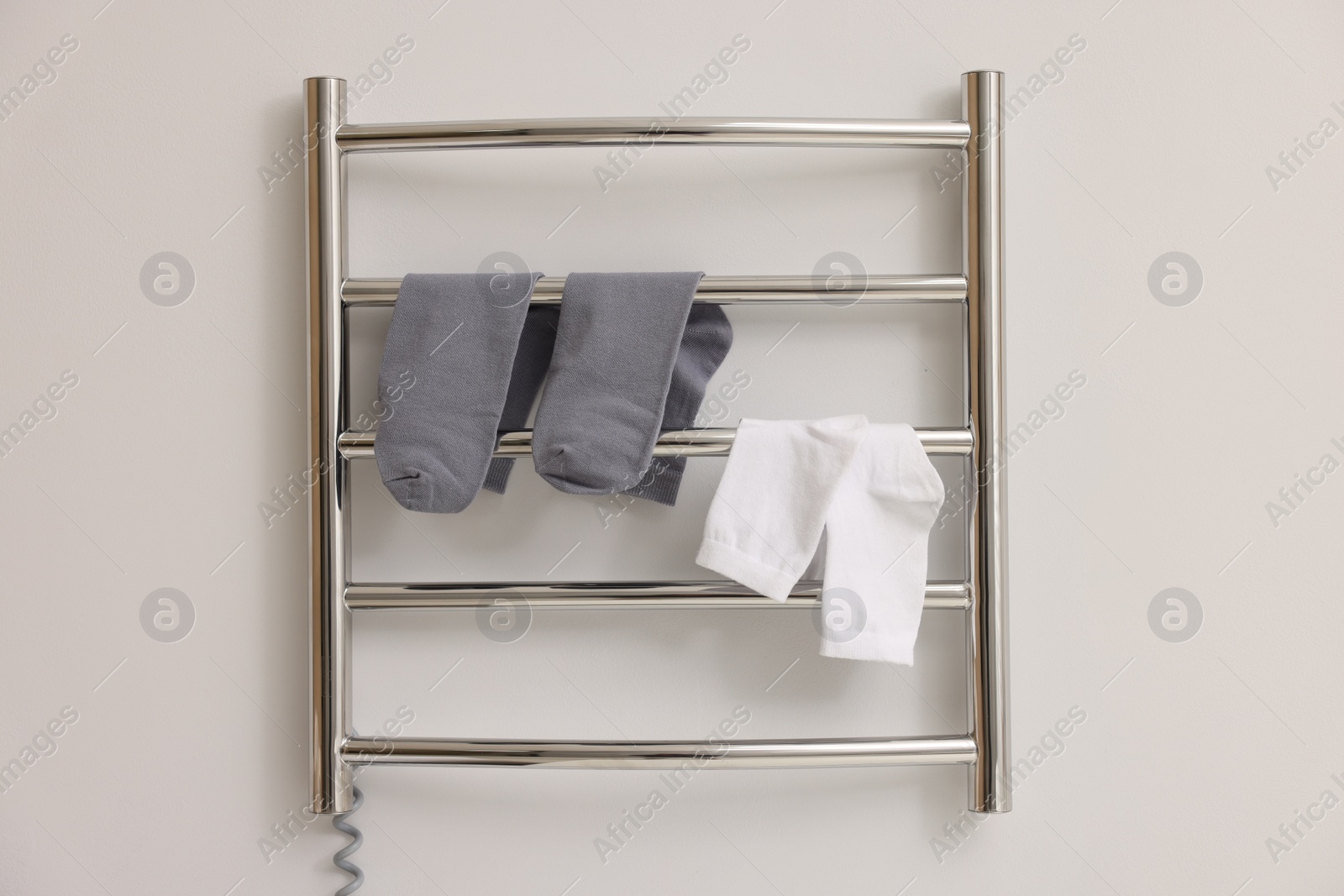 Photo of Heated towel rail with socks on white wall