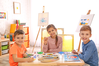 Photo of Cute little children painting at table in room