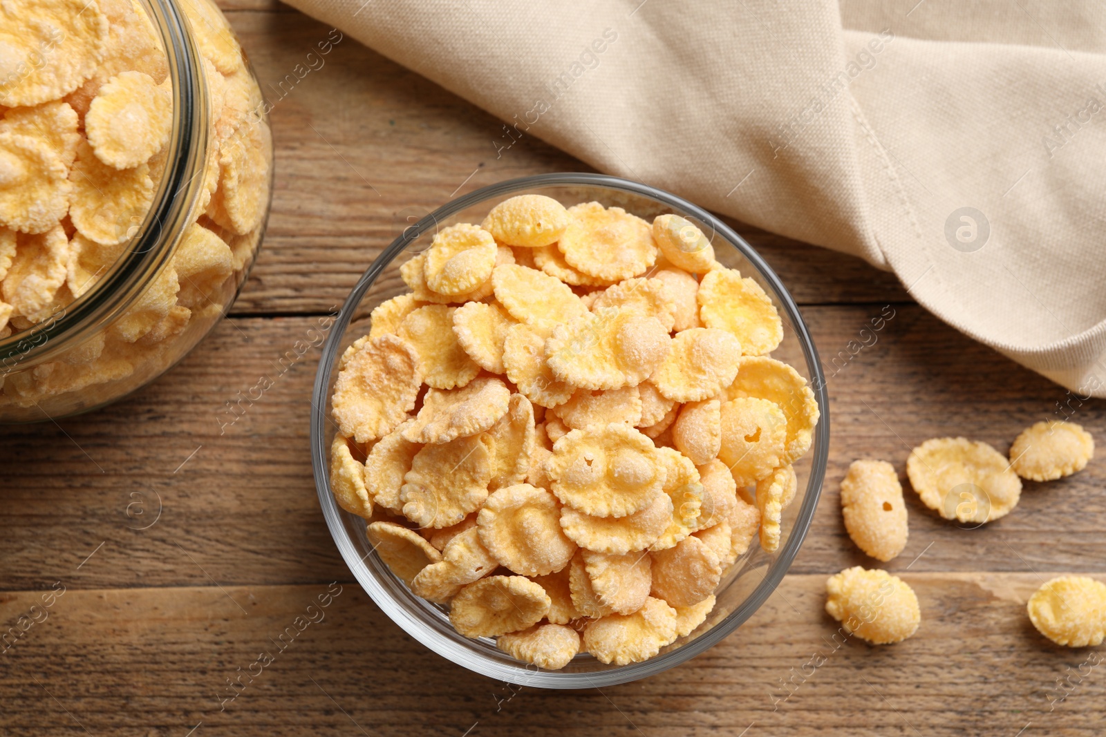 Photo of Bowl with tasty corn flakes on wooden table, flat lay