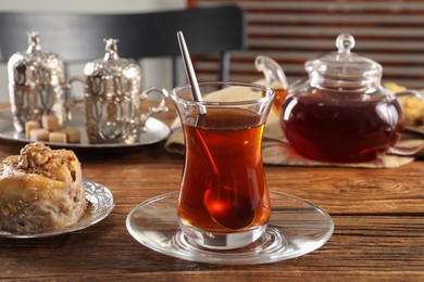 Photo of Turkish tea and sweets served in vintage tea set on wooden table