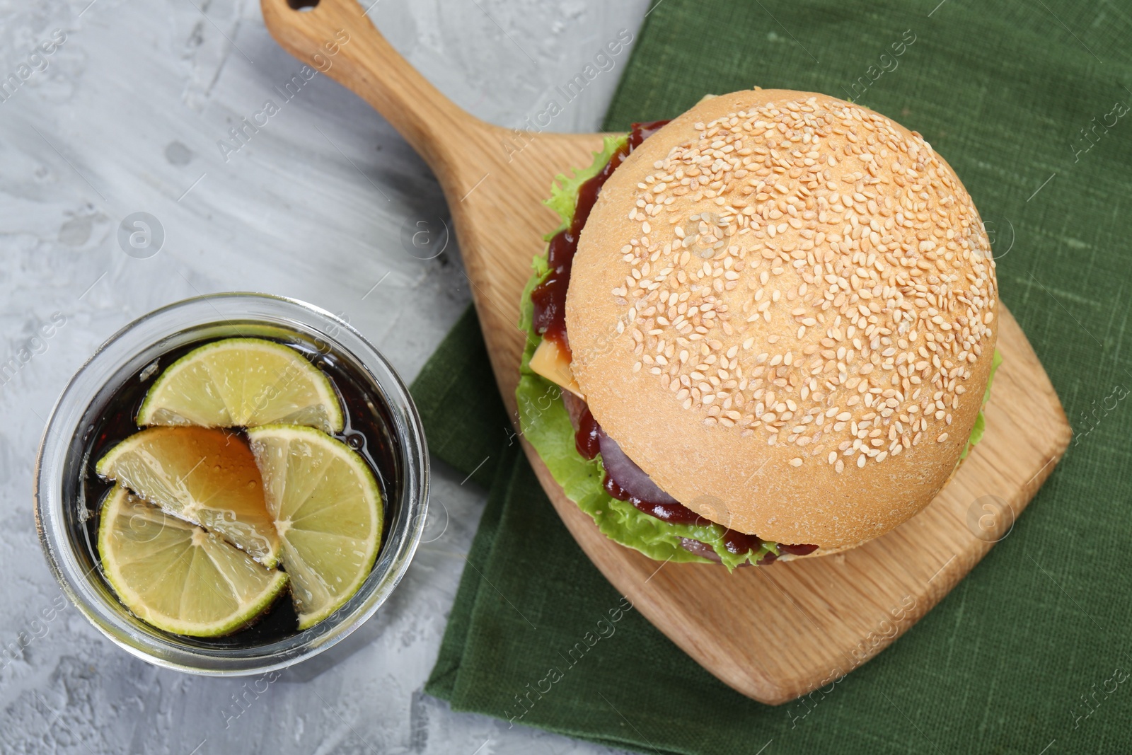 Photo of Delicious cheeseburger and drink on grey textured table, top view