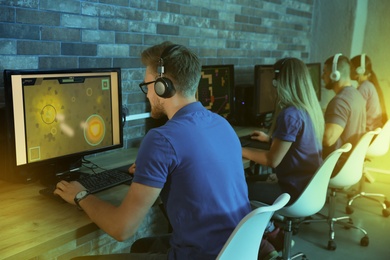 Photo of Group of people playing video games in internet cafe, color tone