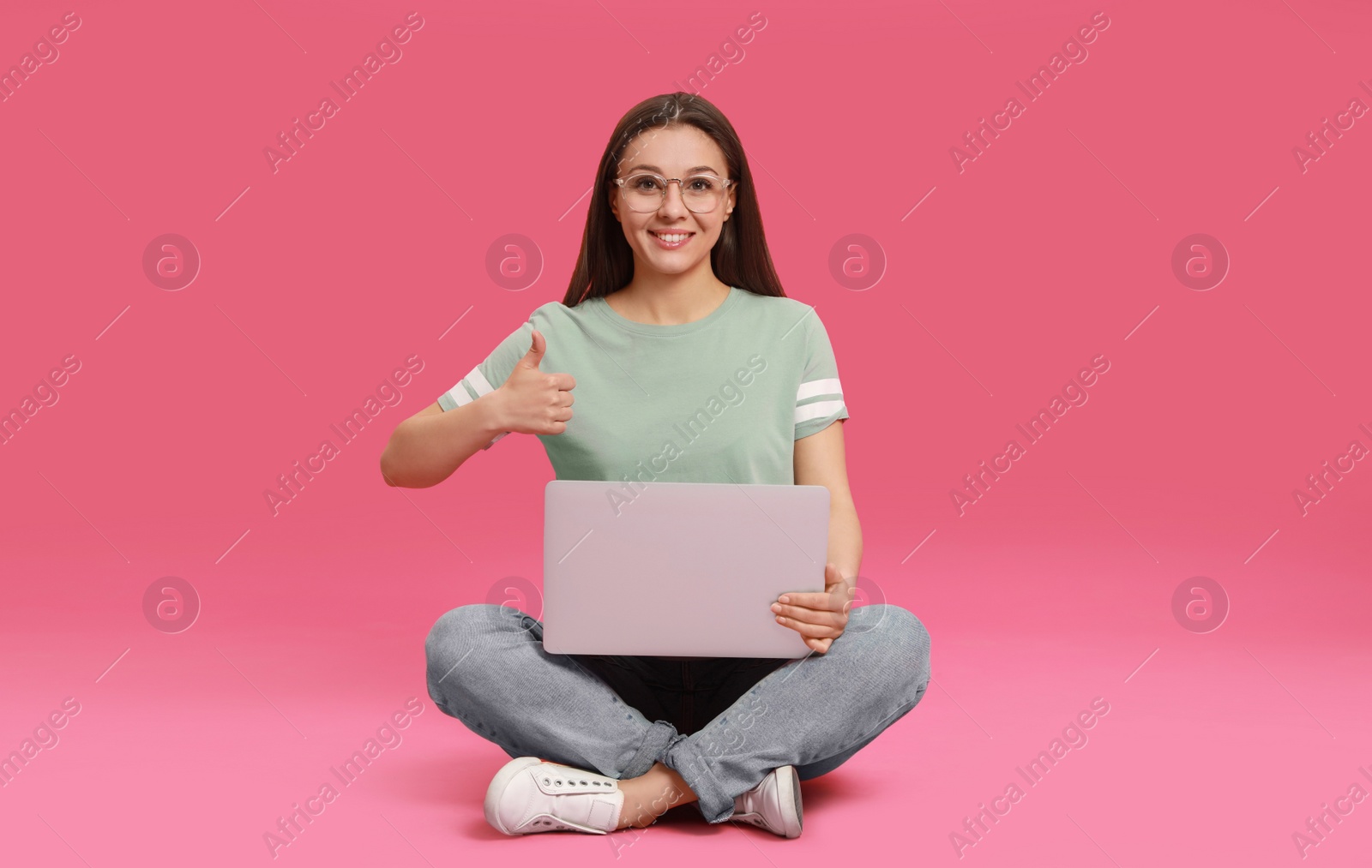 Photo of Young woman with modern laptop on pink background