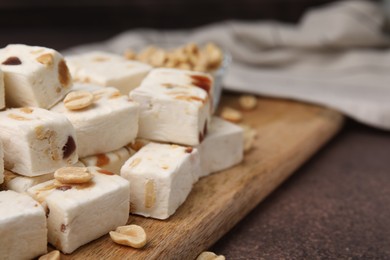 Pieces of delicious nutty nougat on brown table, closeup