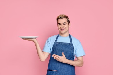 Photo of Portrait of happy confectioner holding empty plate on pink background