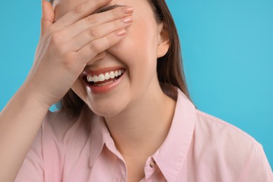 Woman laughing on light blue background, closeup