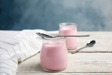 Photo of Glass jars with creamy yogurt served on white wooden table