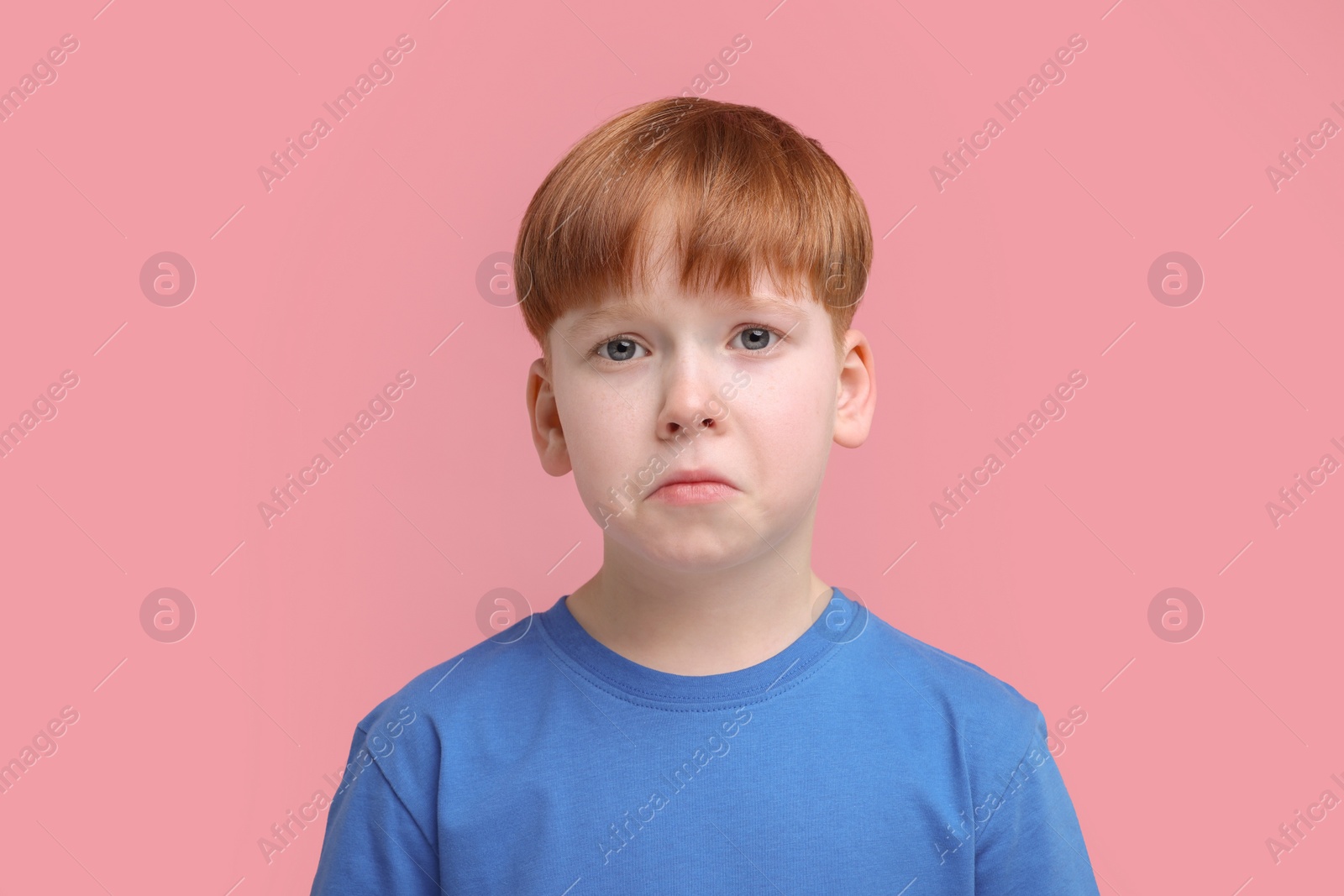 Photo of Portrait of sad little boy on pink background