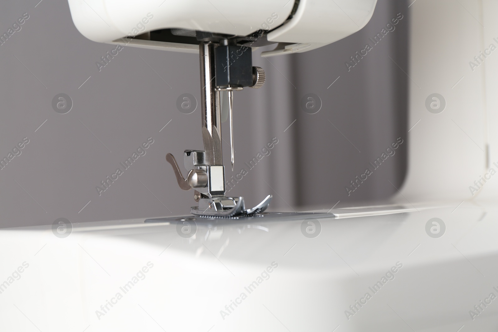 Photo of White sewing machine on gray background, closeup