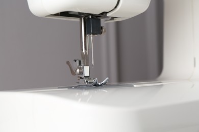 Photo of White sewing machine on gray background, closeup