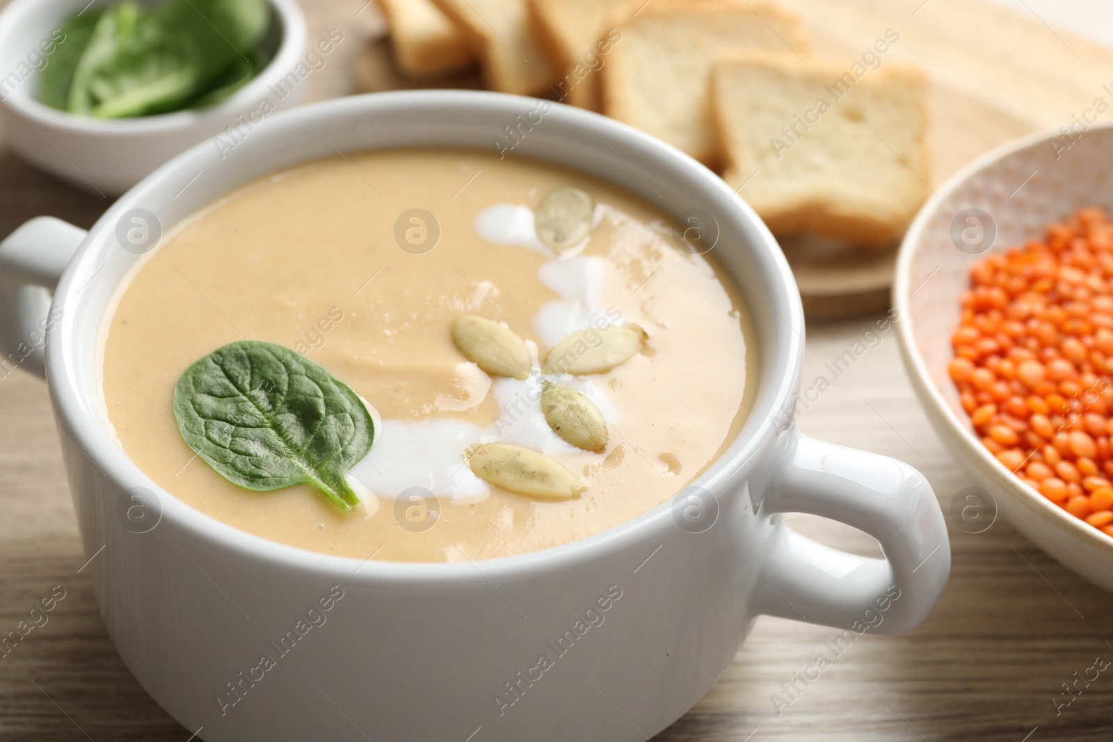 Photo of Healthy cream soup high in vegetable fats on wooden table, closeup