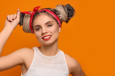 Photo of Beautiful woman with braided double buns on orange background, space for text