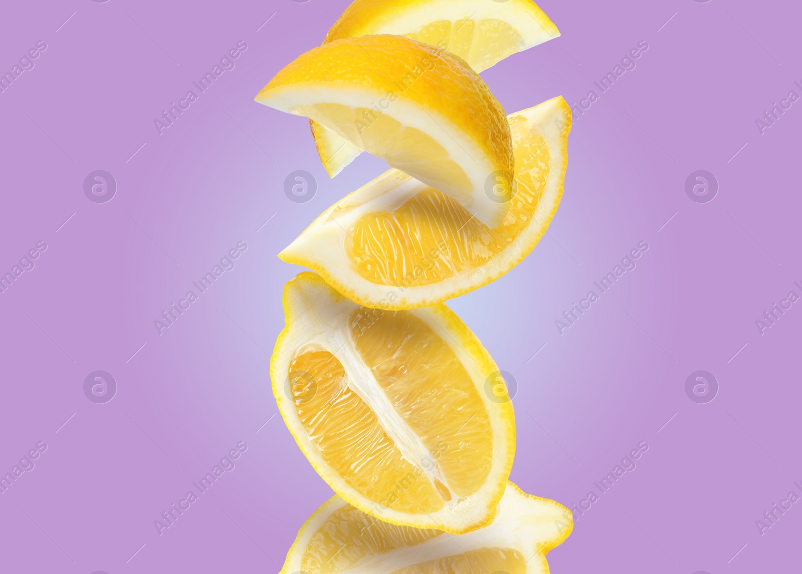 Image of Cut fresh ripe lemons falling on violet background