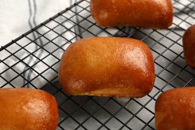 Delicious baked pirozhki on cooling rack, closeup