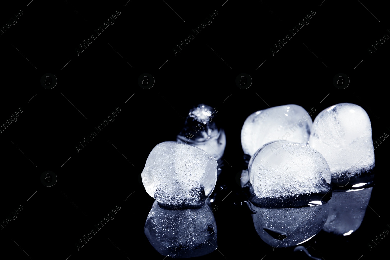 Photo of Melting ice cubes on black background. Space for text