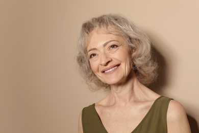 Portrait of mature woman on color background. Space for text