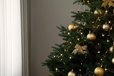 Photo of Christmas tree with beautiful decorations and string lights indoors, space for text