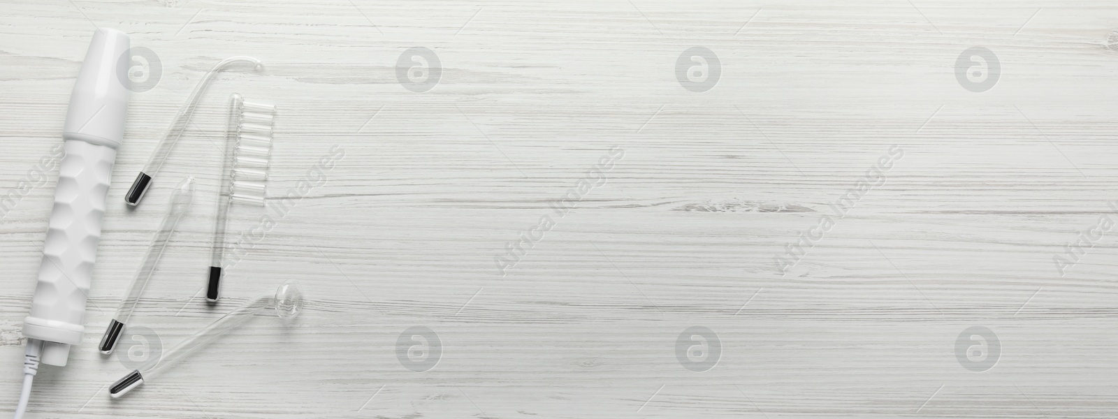 Image of High frequency darsonval device and different nozzles on white wooden background, flat lay. Banner design with space for text