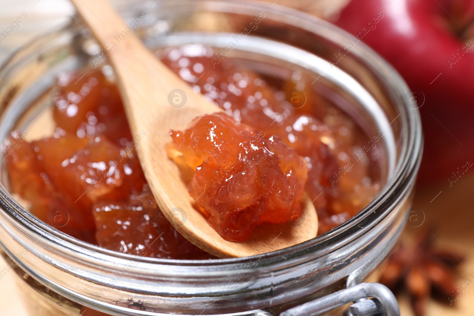 Photo of Delicious apple jam and spoon in jar, closeup