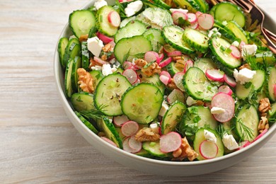 Photo of Bowl of delicious cucumber salad on white wooden table, closeup
