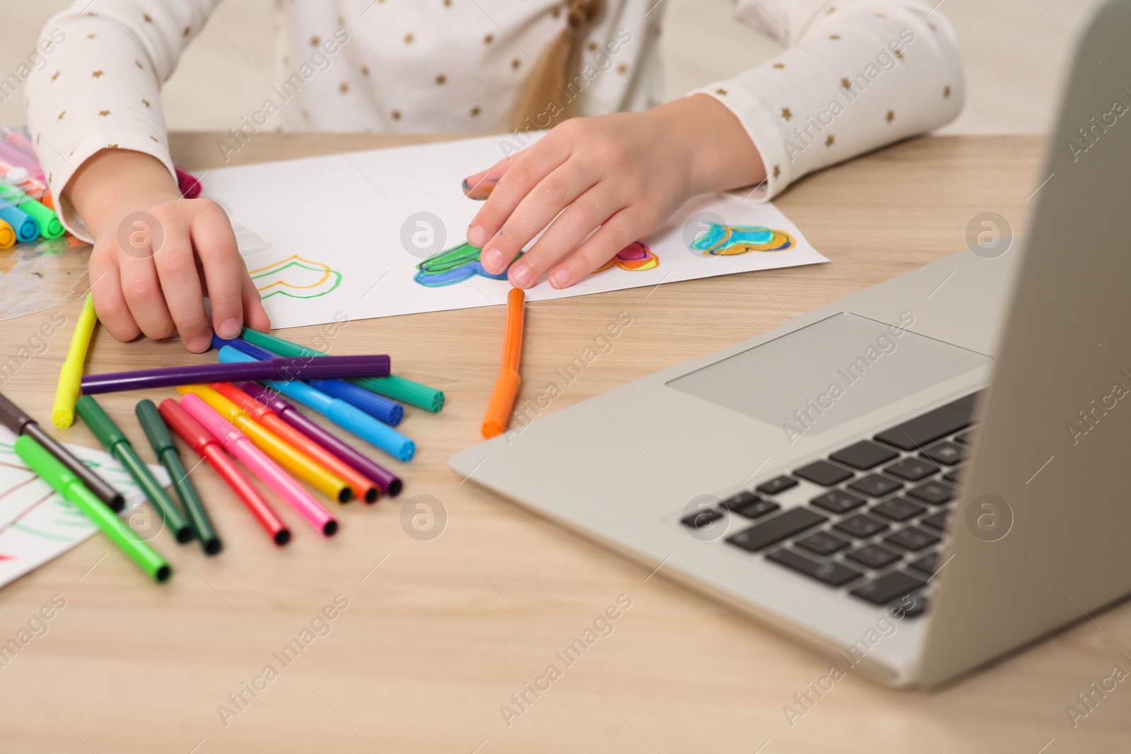 Photo of Little girl drawing with felt-tip pen following online course at home, closeup. Time for hobby