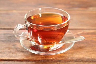 Photo of Glass cup of tea and spoon on wooden table