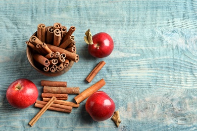 Fresh apples and cinnamon sticks on wooden table, top view