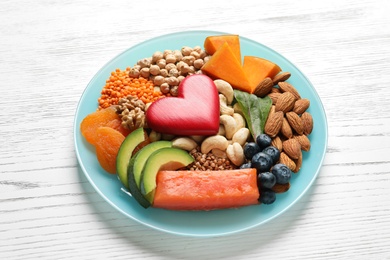 Plate with heart-healthy products on wooden background