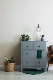Photo of Room interior with grey chest of drawers near beige wall