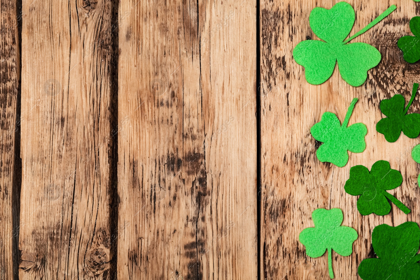 Photo of Decorative clover leaves on wooden table, flat lay with space for text. Saint Patrick's Day celebration