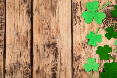 Decorative clover leaves on wooden table, flat lay with space for text. Saint Patrick's Day celebration